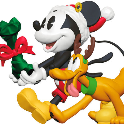 Mickey Mouse holding a dog bone gift walks beside Pluto in reindeer antlers in this cheerful Disney Hallmark Christmas ornament.