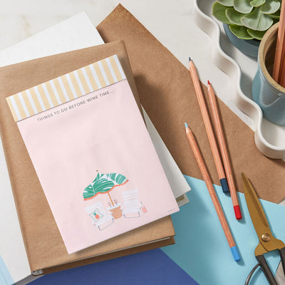 Pink to-do note pad with wine glasses, beach chairs, umbrella, and tropical leaf accents on a striped header.

