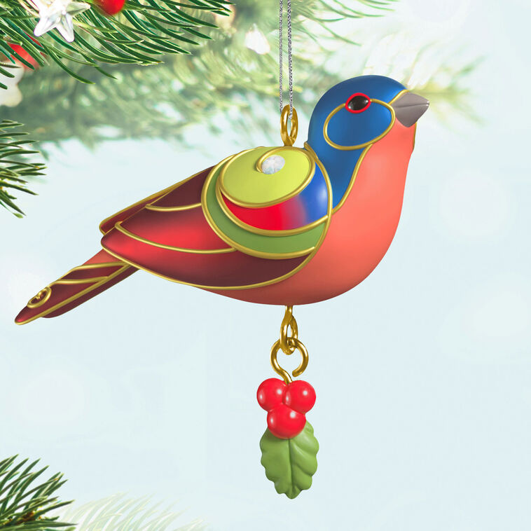 Painted Bunting miniature Christmas tree ornament with colorful feathers, metallic gold trim, and dangling holly berry charm