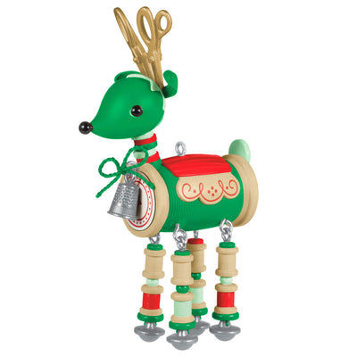Green reindeer ornament made of red and green thread spools with gold scissors antlers, button tail, and silver thimble bell


