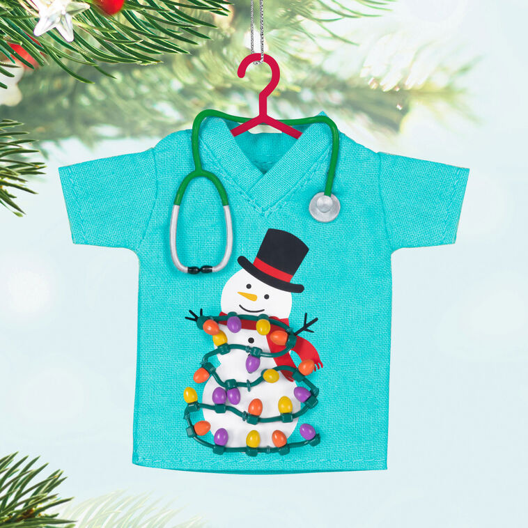 Teal fabric scrubs ornament with snowman and Christmas lights, stethoscope detail, honoring healthcare workers

