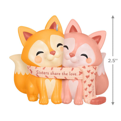 2025 Christmas ornament with two foxes snuggled in a heart-patterned scarf, celebrating sisterly love

