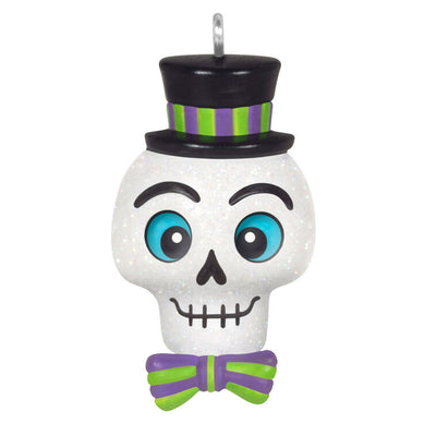 Mini Halloween skull ornament wearing sparkly top hat and bow tie with purple and green accents

