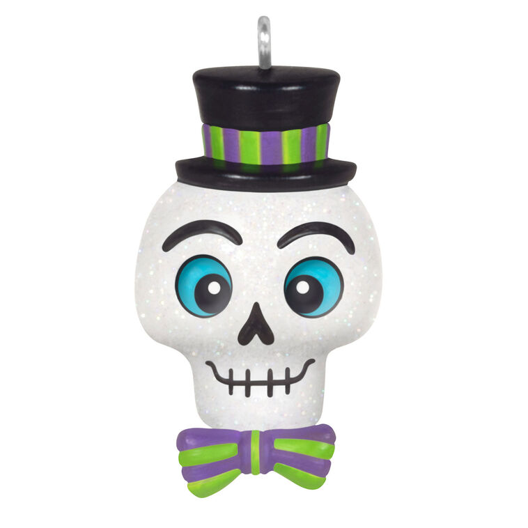 Mini Halloween skull ornament wearing sparkly top hat and bow tie with purple and green accents

