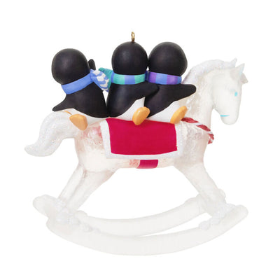 Christmas ornament of playful penguins on a sparkling rocking horse with red and white monogrammed saddle