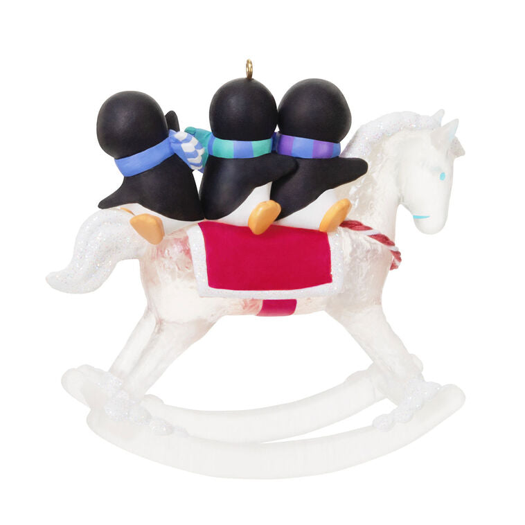 Christmas ornament of playful penguins on a sparkling rocking horse with red and white monogrammed saddle