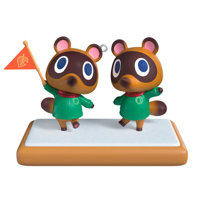 Hallmark Keepsake Nintendo Animal Crossing Timmy and Tommy ornament, twin raccoons with flag, green jackets, red scarves, on wood-style base.