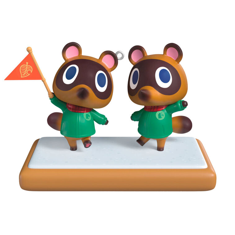 Hallmark Keepsake Nintendo Animal Crossing Timmy and Tommy ornament, twin raccoons with flag, green jackets, red scarves, on wood-style base.