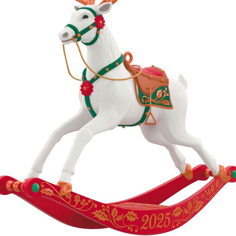 White reindeer Christmas ornament with bronze antlers and hooves, red flower accents, green bridle, on rocking stand

