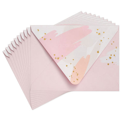 Pink envelopes with white and pink brushstroke flap design and scattered gold foil dot accents, featuring pointed flaps.
