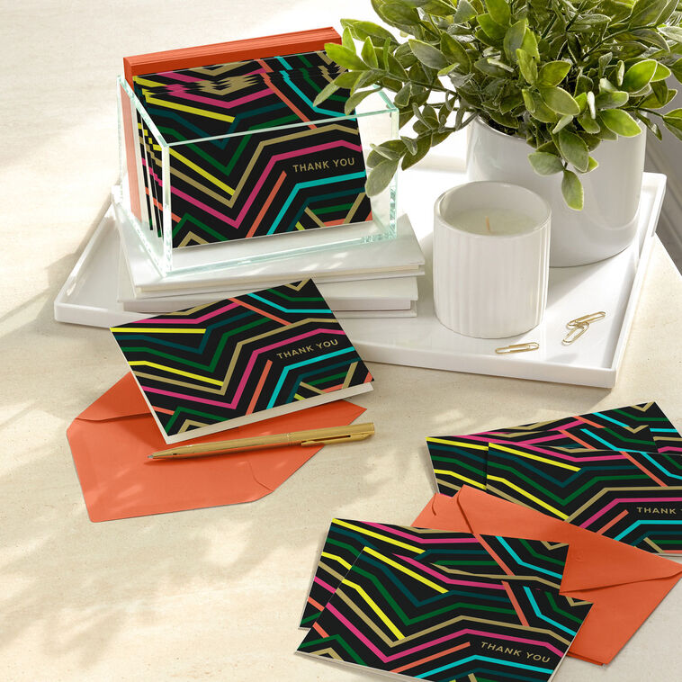 Black thank-you cards with angular neon lines in bold colors and gold foil lettering.
