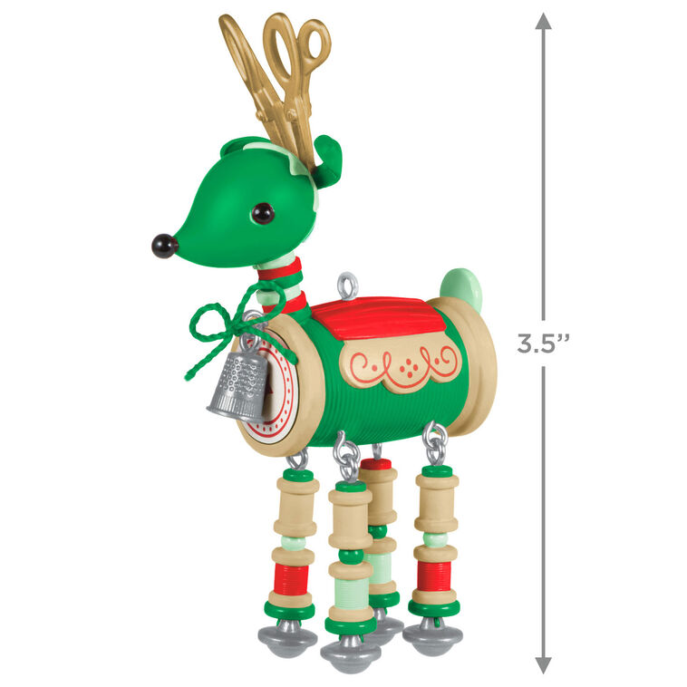 Green reindeer ornament made of red and green thread spools with gold scissors antlers, button tail, and silver thimble bell


