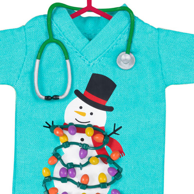 Teal fabric scrubs ornament with snowman and Christmas lights, stethoscope detail, honoring healthcare workers


