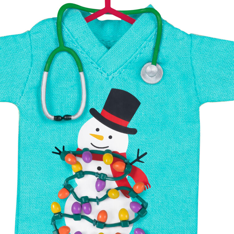 Teal fabric scrubs ornament with snowman and Christmas lights, stethoscope detail, honoring healthcare workers

