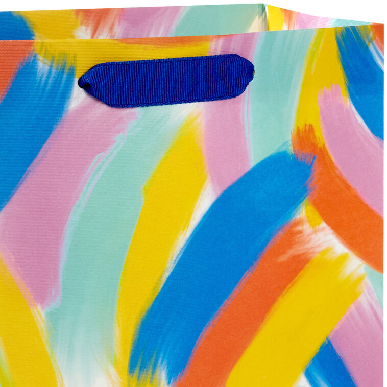 Hallmark medium gift bag with colorful abstract brushstroke rainbows in purple, blue, yellow, and orange on a white background