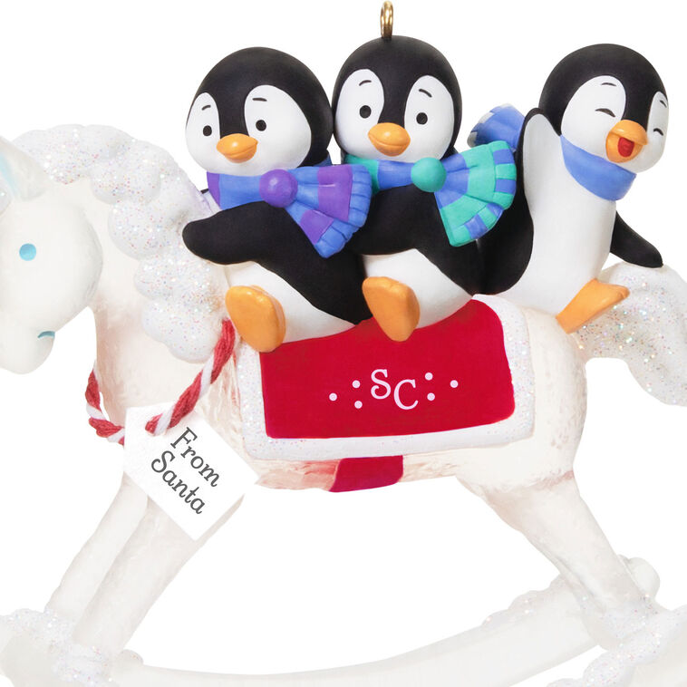 Christmas ornament of playful penguins on a sparkling rocking horse with red and white monogrammed saddle