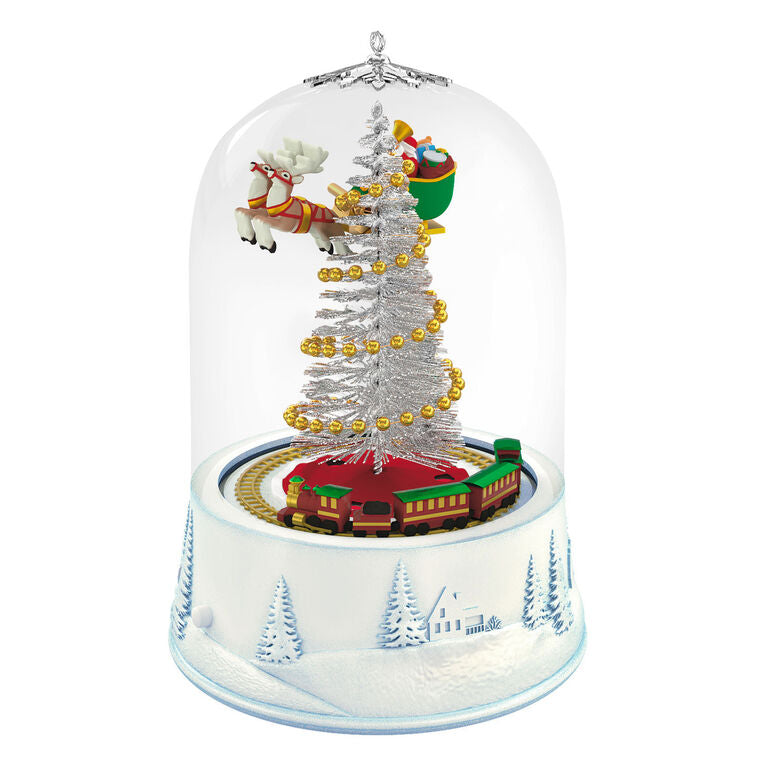 Santa sleigh and toy train under glass dome with lights and motion on snowy village base