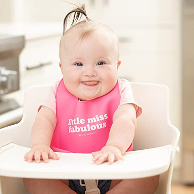 Soft silicone baby bib in pink with “Little Miss Fabulous” print and deep food-catching pocket, adjustable neck closure.

