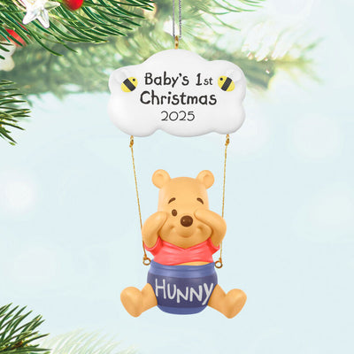 Winnie the Pooh Christmas ornament swinging under a "Baby’s 1st Christmas 2025" cloud with hunny pot and bee accents