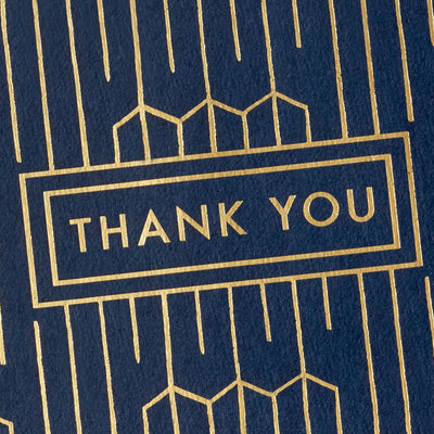 Navy blue thank-you cards with gold foil geometric lines and matching envelopes in kraft box.
