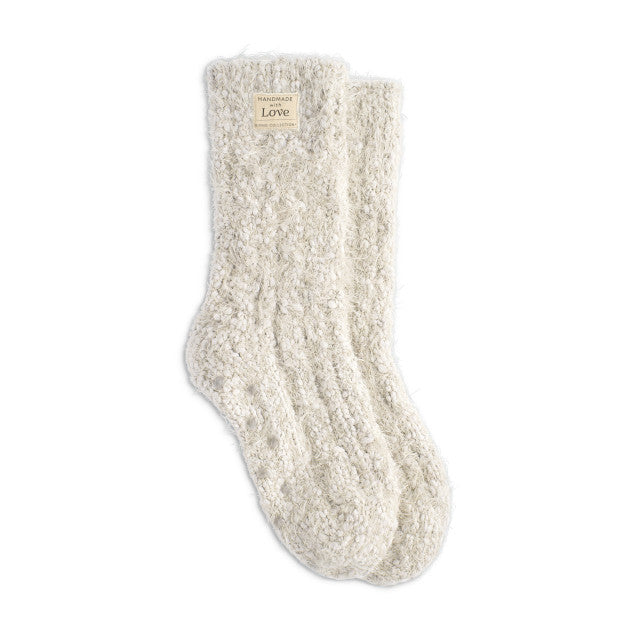 Cream fuzzy women’s socks with rubber grippers on the soles, ultra-soft and cozy, part of the Demdaco Giving Collection.