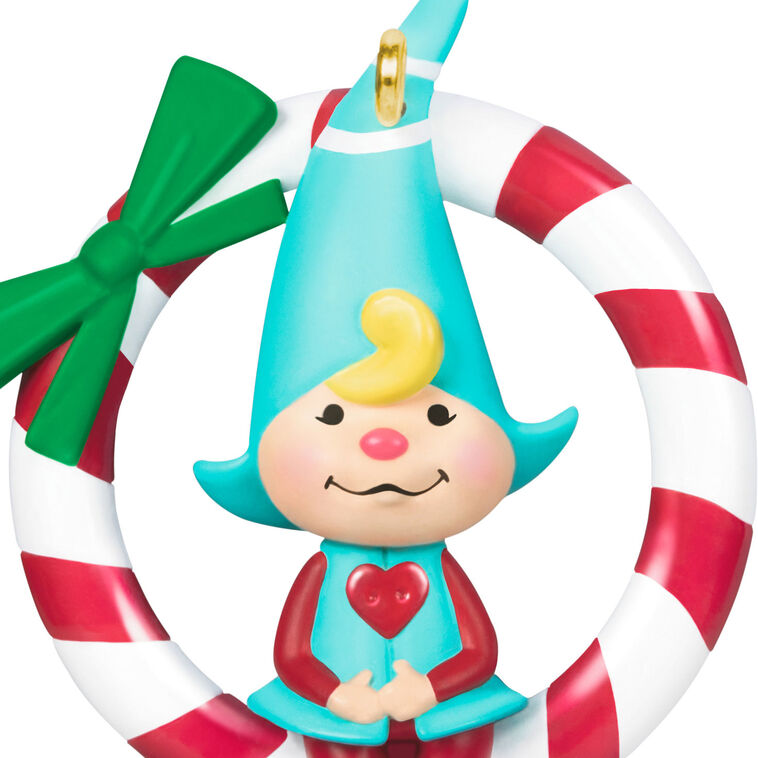 Hallmark Keepsake Sweet Peppermint girl gnome ornament in red and blue, sitting on candy cane wreath with green bow.
