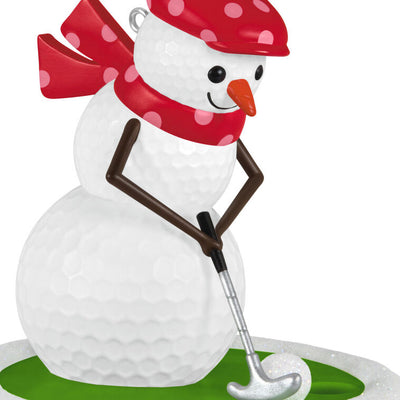 Golf ball snowman ornament in red polka dot hat and scarf, hitting a snowball with a silver putter

