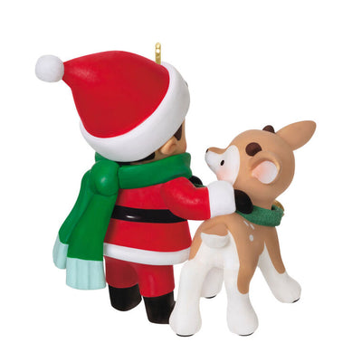 Hallmark Keepsake Young Santa ornament—Santa as a boy in red hat and coat, green scarf, placing green collar with gold bell on young reindeer
