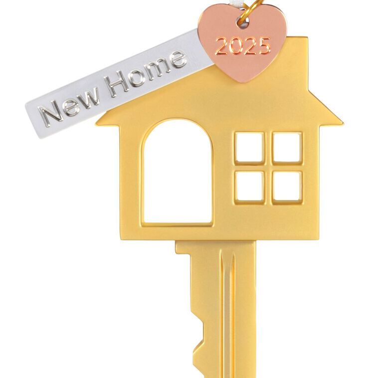 Gold metal key ornament shaped like a house with a pink heart and “New Home” banner charm, for new homeowners.