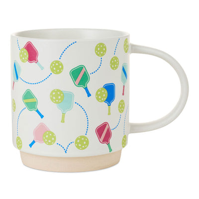 White ceramic pickleball mug with colorful paddle and ball icons, oversized handle, and stackable recessed base