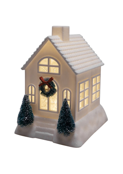 Assorted ivory and pink glittery Christmas houses with bottlebrush trees, wreaths, and warm light.
