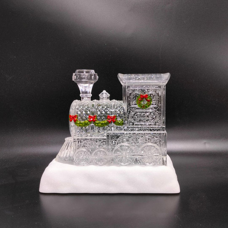 Glittering LED Christmas train with wreath accents, snowy base, and warm interior glow.
