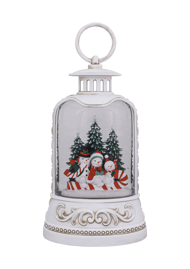 White lantern with snowman family, candy canes, snowy trees, and swirling glitter glow.
