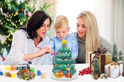 DIY ceramic Christmas tree painting kit with white tree, six paint pots, two brushes, and colorful light bulbs.