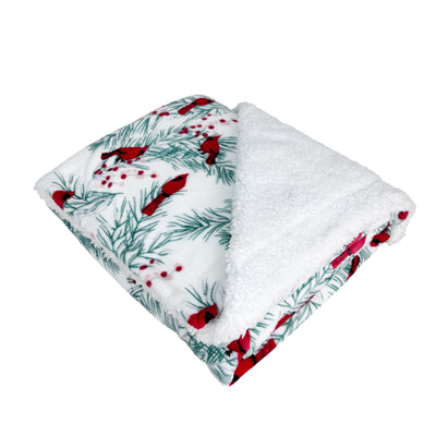 White fleece Sherpa blanket with red cardinals, holly, and pine branches on soft velvety fabric.