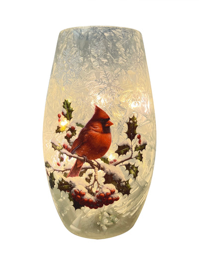 Glowing crackled glass vase with red cardinal perched on snowy winter branches.
