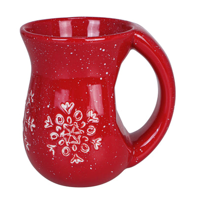 Cranberry red ceramic mug with white snowflake pattern and rounded body with large handle.