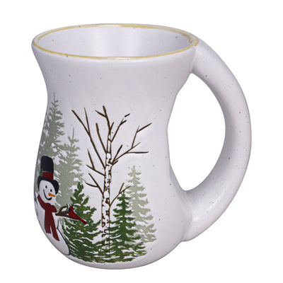 White ceramic mug with balsam and cedar tree artwork and a smiling snowman illustration, curved shape and handle.