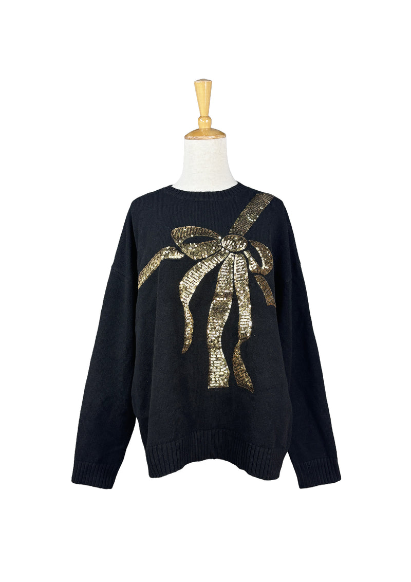 Black sweater with oversized gold sequin bow across the chest, displayed on mannequin.