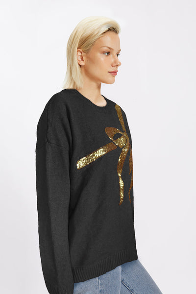 Black sweater with oversized gold sequin bow across the chest, displayed on mannequin.