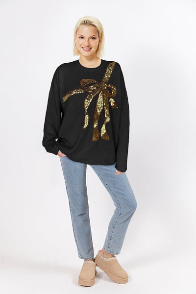 Black sweater with oversized gold sequin bow across the chest, displayed on mannequin