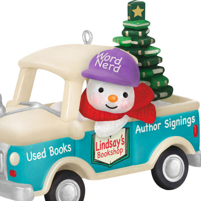 Hallmark Keepsake Holiday Parade 2025 ornament—snowman with “Word Nerd” hat drives bookshop pickup truck hauling Christmas tree made of books
