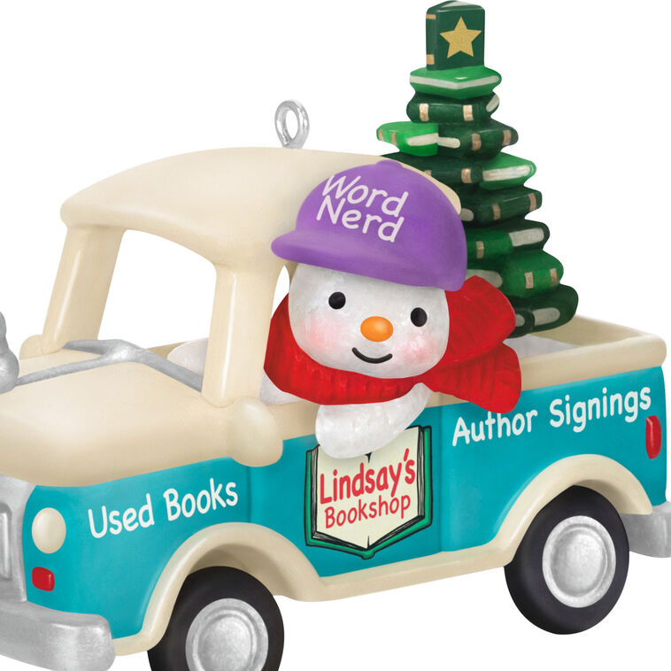 Hallmark Keepsake Holiday Parade 2025 ornament—snowman with “Word Nerd” hat drives bookshop pickup truck hauling Christmas tree made of books
