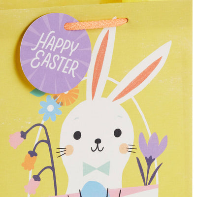 Hallmark Easter gift bag with white bunny in pastel basket on yellow background and floral accents.