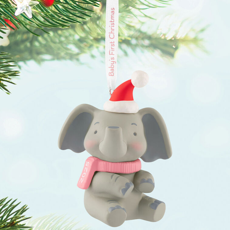 Gray elephant ornament in Santa hat and pink scarf holds a “Baby’s First Christmas 2025” ribbon.