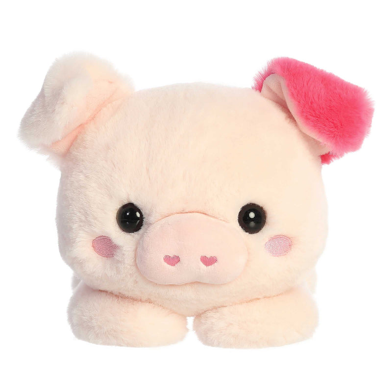 Penelope Pig plush by Aurora, in soft pink with red ear accents, lying belly-down in a cuddly Valentine’s Day pose.