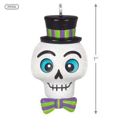 Mini Halloween skull ornament wearing sparkly top hat and bow tie with purple and green accents

