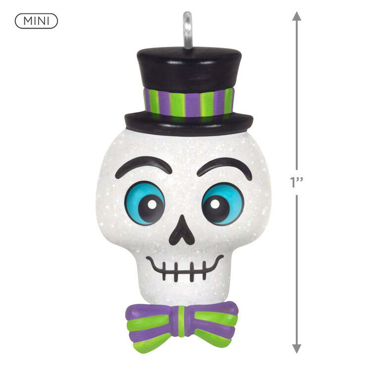 Mini Halloween skull ornament wearing sparkly top hat and bow tie with purple and green accents

