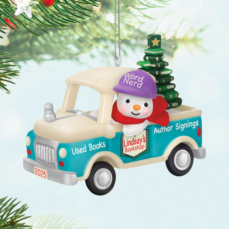 Hallmark Keepsake Holiday Parade 2025 ornament—snowman with “Word Nerd” hat drives bookshop pickup truck hauling Christmas tree made of books
