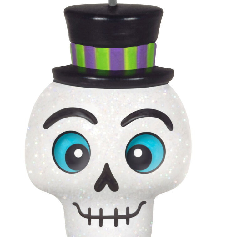 Mini Halloween skull ornament wearing sparkly top hat and bow tie with purple and green accents

